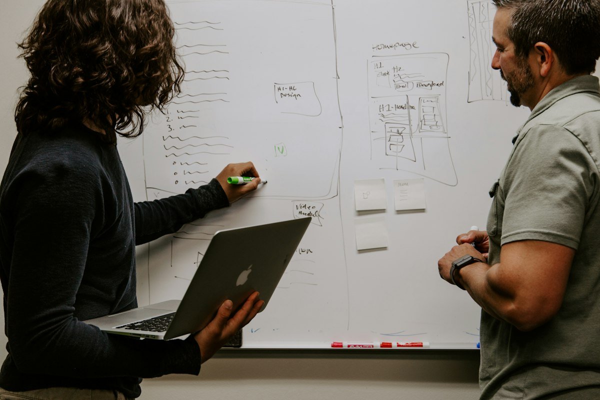 Deux collègues planifiant un projet devant un tableau blanc