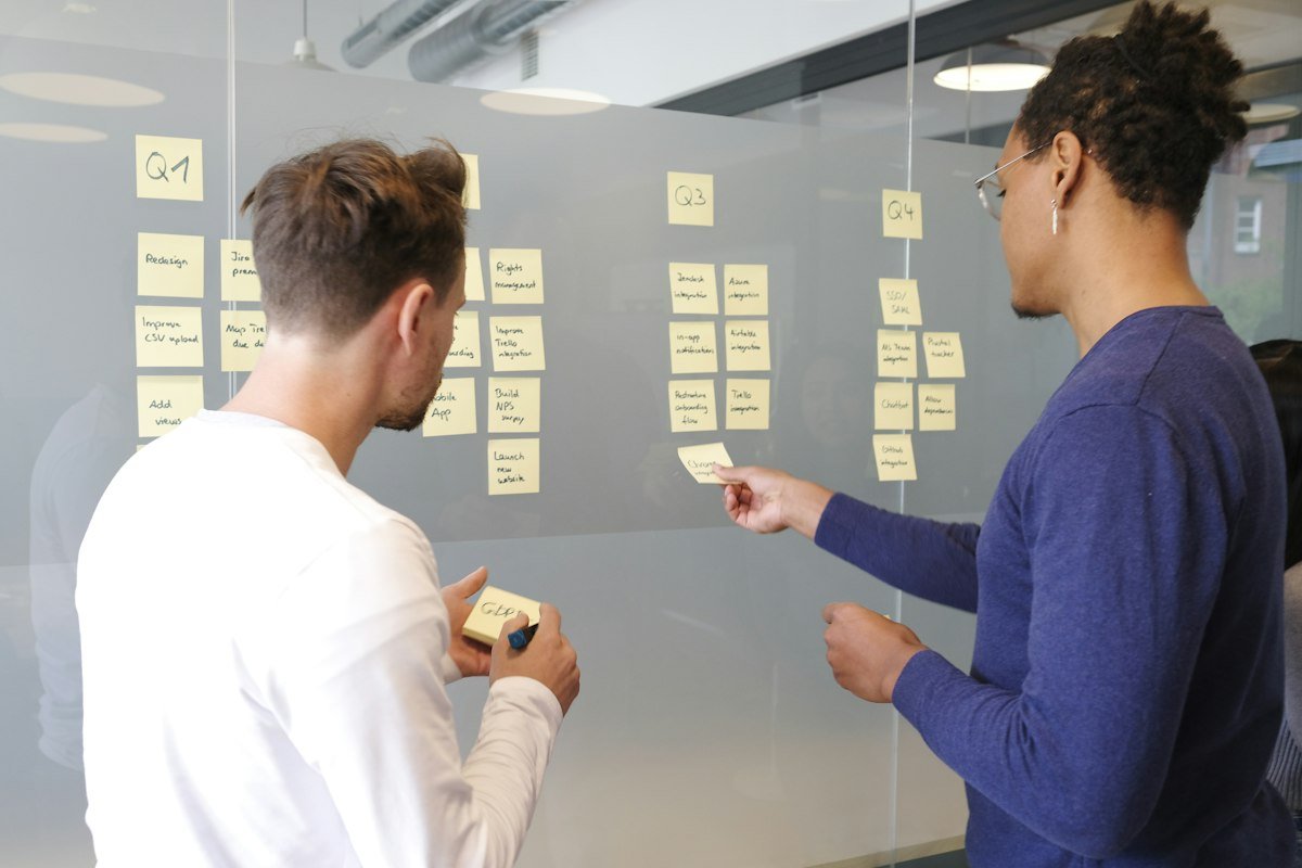 Deux personnes planifiant un projet sur un tableau de notes adhésives